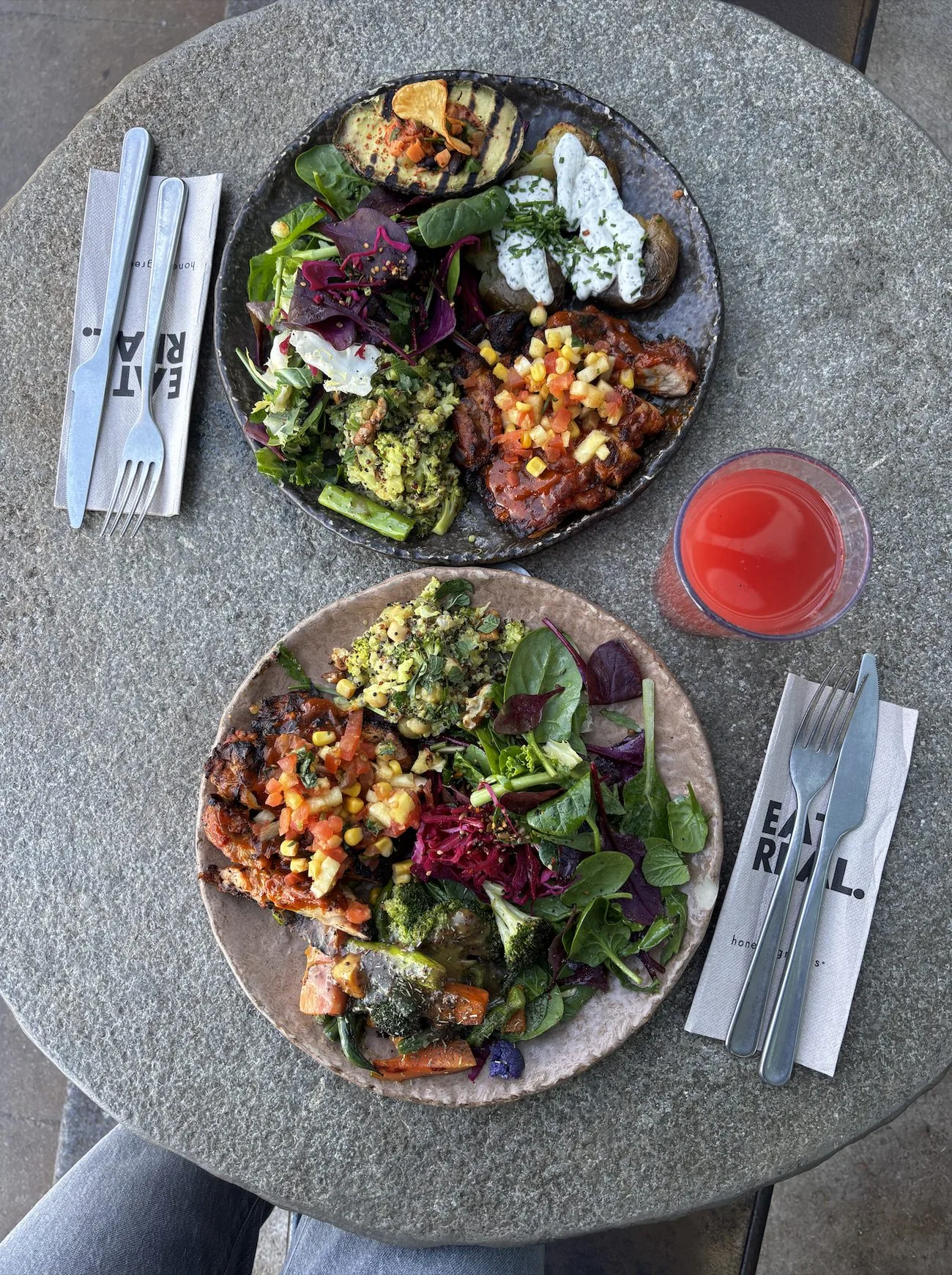 Deux assiettes colorées de légumes, salades et protéines sur une table en pierre